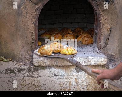 Traditional Cypriot easter pastries made with mixture of various cheese and halloumi, baked in clay oven using a wooden peel flaounes flaouna Stock Photo