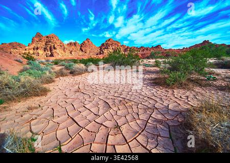 Cracked Desert Ground Red Rocks and Blue Sky in Valley of Fire Nevada Stock Photo