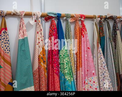 A row of vibrant textile swatches with various patterns and prints tied to a wooden pole. This display showcases a creative assortment of cloth materi Stock Photo