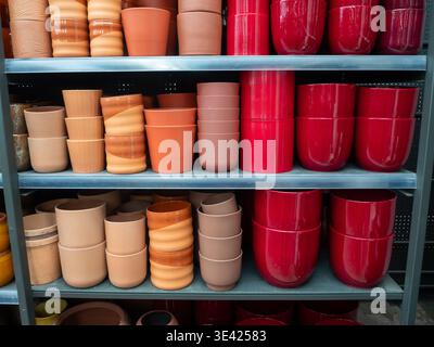 An organized retail display showcasing various plant pots arranged in rows on metal shelves. The assortment includes rustic terracotta and unglazed cl Stock Photo