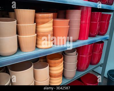 An organized retail display showcasing various plant pots arranged in rows on metal shelves. The assortment includes rustic terracotta and unglazed cl Stock Photo