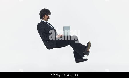 Businessman floating while using laptop isolated on white background studio shot. Stock Photo