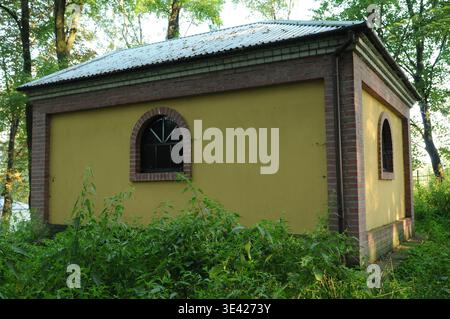 Close-up of a traditional Jewish ohel with yellow walls and brick finish at the Jewish cemetery in Dynow, Poland. Stock Photo