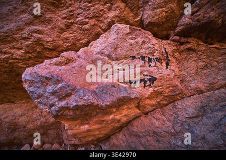 Arrow Marker On Red Rock Wall With Rough Texture And Desert Canyon Backdrop Stock Photo