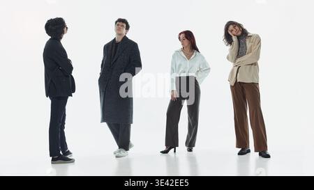Group of stylish men and women standing in different poses in minimal studio. Stock Photo