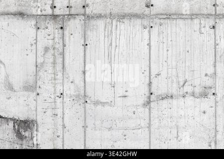 High-resolution concrete wall texture featuring vertical panel lines, bolt marks, stains and subtle cracks. Neutral industrial background ideal for ar Stock Photo