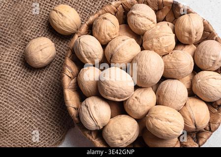 Whole Walnuts In Round Wicker Basket, top view. Basket of walnuts. Paleo diet and healthy eating concept. Stock Photo