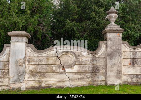 Old weathered stone wall with a vertical crack in a historic park Stock Photo