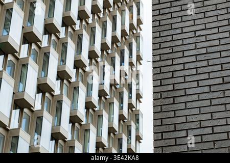 Modern building facade with repetitive window pattern next to contrasting brick wall Stock Photo