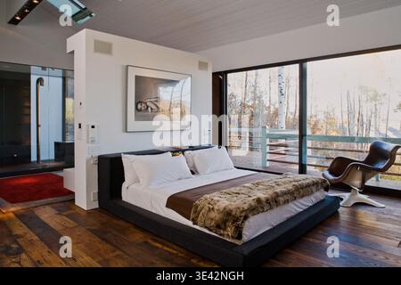 Modern bedroom with large window and forest view. Stock Photo