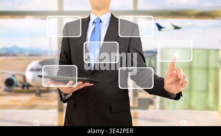 man is using tablet pc, pressing on virtual screen and selecting contact us at airport departure lounge Stock Photo