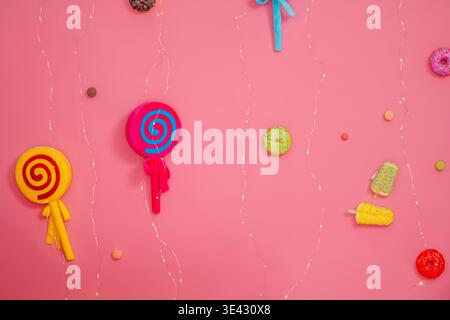 Colorful Lollipops On Pink Wall, Hanging Swirl Candies And Novelty Sweets Creating Playful Pattern Stock Photo