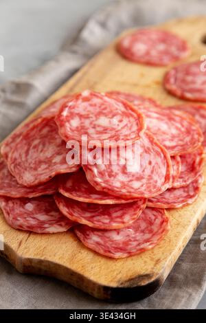 Spanish Salchichon Sausage on a Wooden Board, side view. Close-up. Stock Photo