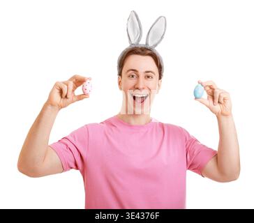 Excited young man wearing bunny ears holding two colorful painted Easter eggs. Isolated on a white background. Happy spring holiday celebration concep Stock Photo