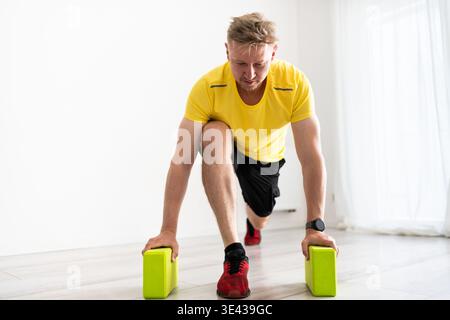 Young Man Doing Routine Sport At Home With Yoga Blocks Stock Photo
