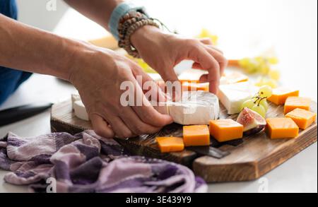 Girl Adds Brie Cheese To A Cheese Plate With Cheddar Cheese And Figs Stock Photo