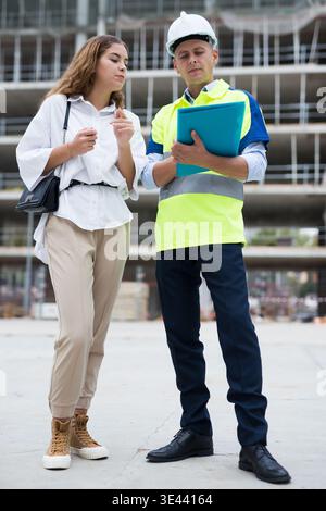 Builder talking with client at construction site Stock Photo