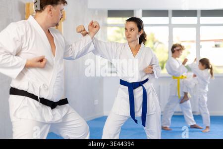 Determined female karateka working on hand strikes in sparring with husband Stock Photo