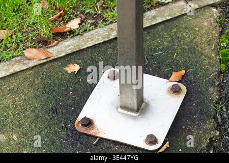 Close up of metal base plate secured with rusted bolts on pavement. Concept of construction, durability, wear, and infrastructure Stock Photo