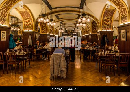 Dining room at Auerbachs Keller: a long vaulted hall with ornately painted arches, pendant lights and parquet flooring; guests having dinner, waiters at work. The restaurant has been in existence since 1525. Leipzig, Saxony, Germany Stock Photo