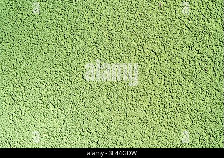 Close-up of lime green stucco facade wall with coarse grain background. Background of painted textured wall, textured surface with rough finish Stock Photo
