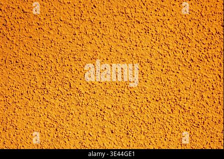 Close-up of  orange stucco facade with coarse grain background. Background of painted textured wall, textured surface with rough finish Stock Photo