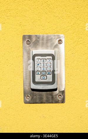 Modern digital keypad door lock on yellow stucco wall. Security access control system for building entrance Stock Photo