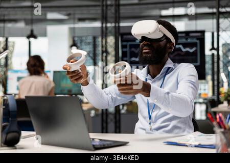 African American financial consultant uses VR goggles for augmented reality business analytics. Male office worker managing data in immersive virtual environment for project planning. Stock Photo