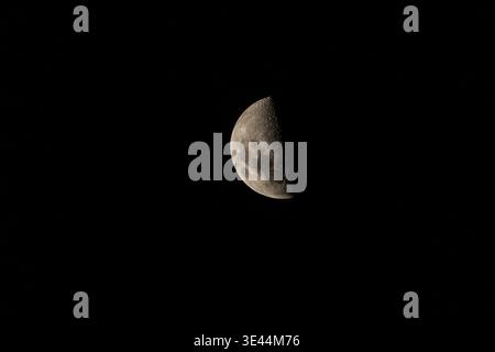 Half moon phase isolated in black sky with detailed craters Stock Photo