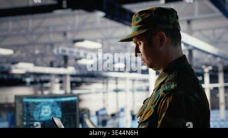 Army software developer in server hub uses artificial intelligence app on laptop to review reconnaissance information. Military data center employee uses neural networks to plan mission, camera B Stock Photo