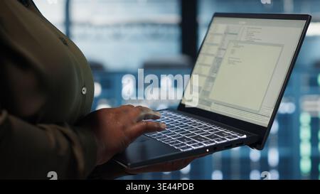 Close up of software developer working in data center to optimize network infrastructure. Programmer in server farm diagnosing and resolving equipment malfunctions using device Stock Photo