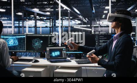 Programmer using VR goggles in data center, coding with generative AI assistance. IT specialist using virtual reality, leveraging artificial intelligence large language model to solve tasks, camera A Stock Photo