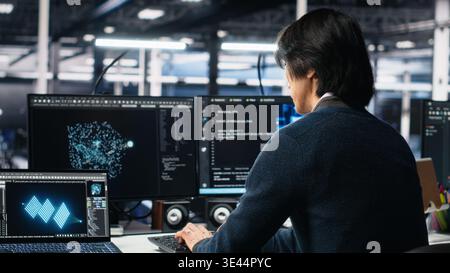 Admin entering data center office, reviews AI diagnostics on computer. IT expert starting work at server farm desk, optimizing artificial intelligence systems configuration, camera A Stock Photo