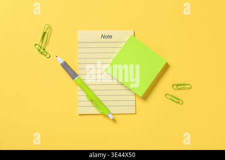 Blank note and sticky notes with pen on yellow background Stock Photo