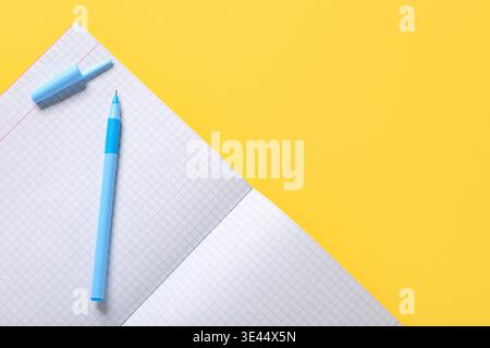 Open notebook with pen on yellow background Stock Photo