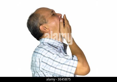 Portrait of sleepy Asian Man wearing shirt and covering his mouth with hand while yawning. Isolated on white background Stock Photo