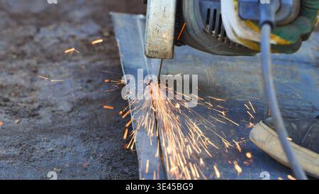 Worker using an angle grinder to cut metal, creating a shower of fiery sparks Stock Photo