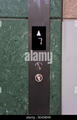 Elevator panel with floor indicator showing 7th floor, modern metallic control buttons, green Stock Photo