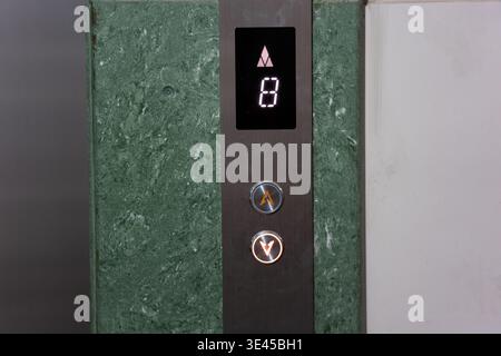 Elevator panel showing floor 8 with upward arrow, green marble wall, modern building interior in Stock Photo