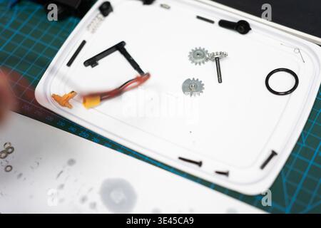 RC Car Parts and Gears on White Tray Over Green Cutting Mat in Workshop Stock Photo