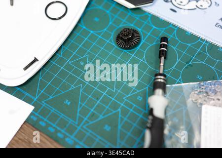 Precision Screwdriver and Gear Component on Green Cutting Mat with Tools and Parts in Workshop Stock Photo