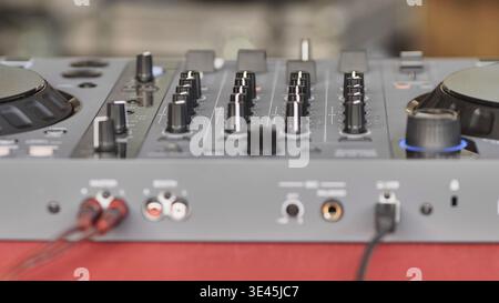 DJ controller with connected cables and knobs for mixing music at an event Stock Photo