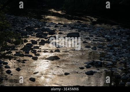 Rocky riverbed on River Swale with light reflecting off the water surface in Swaledale Stock Photo