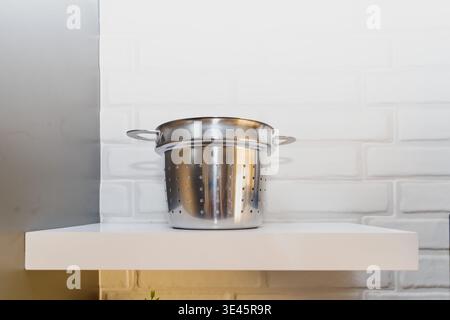 Stainless steel colander on kitchen shelf minimal kitchen interior cooking utensil concept Stock Photo