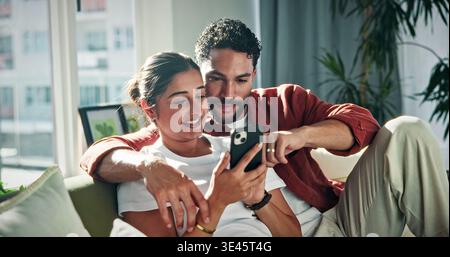 Relax, talking and couple on sofa with phone for social media, networking and bonding on weekend. Marriage, happy and man with woman on smartphone to Stock Photo