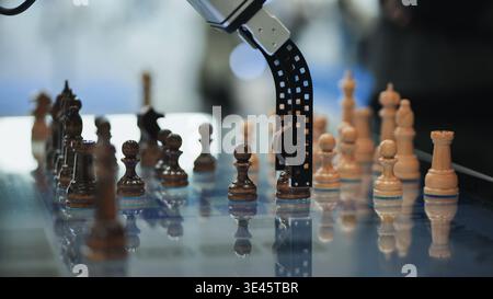 Robot arm moving chess pawn on reflective board, illustrating AI and automation Stock Photo