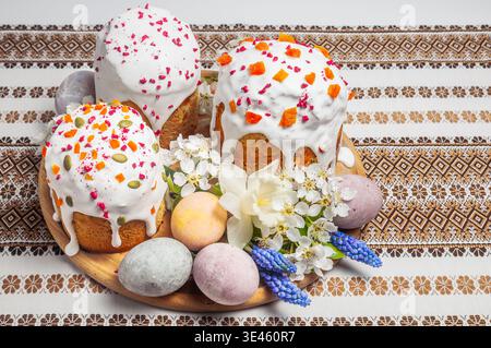 A festive Easter table setting featuring elaborately decorated kulich cakes alongside colorful eggs and delicate floral arrangements, evoking a sense Stock Photo