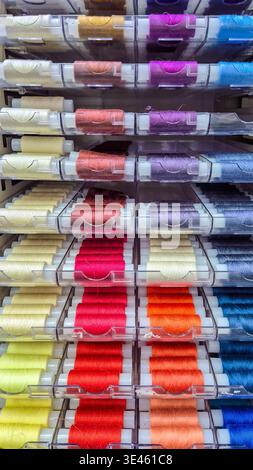 Rows of colorful sewing thread spools in storage drawers, close up. Concept: textile production tools Stock Photo
