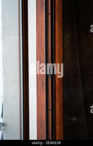 Wooden window or door frame showing security lock, a detail of modern interior architecture and home design focusing on a closed brown wood door Stock Photo