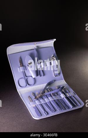 Open leather case with manicure tools: scissors, clippers, files, pusher, and accessories. Metallic parts gleam under light, while soft case texture h Stock Photo